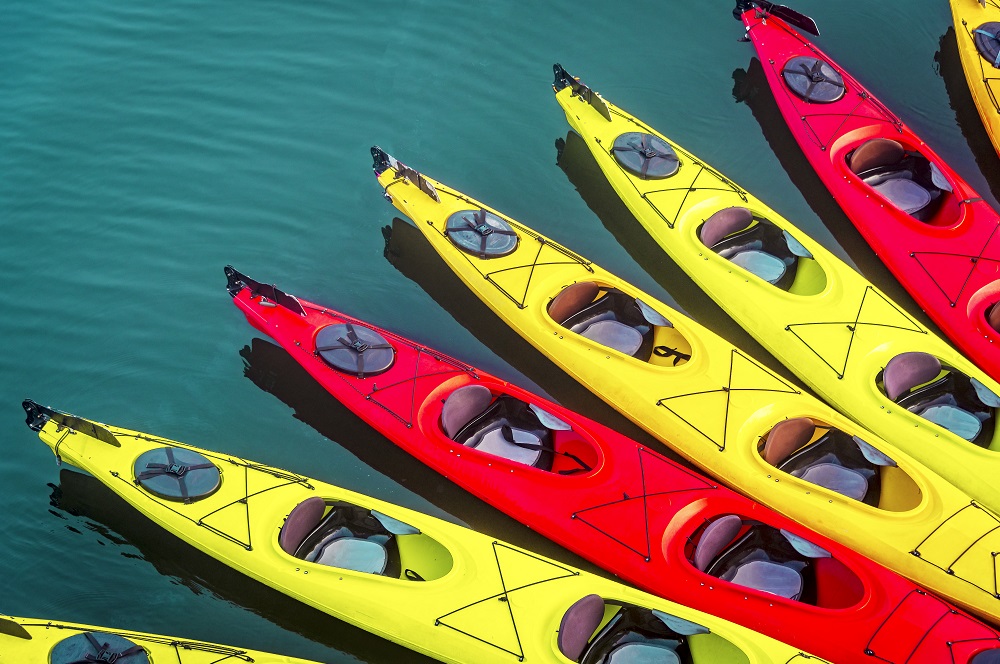 kayak background with many kayaks on the surface of the ocean with red and yellow kayaks