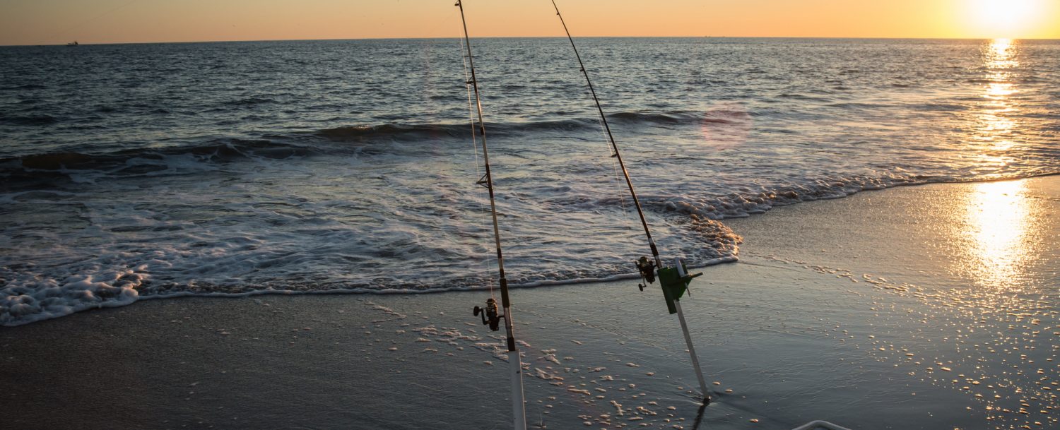 A couple of surf fishing rods stand ready at the beach in NC.