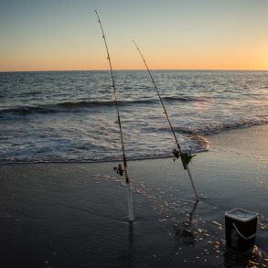 A couple of surf fishing rods stand ready at the beach in NC.