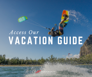 access our vacation guide text. photo of guy kiteboarding colorful board and kite on the ocean 