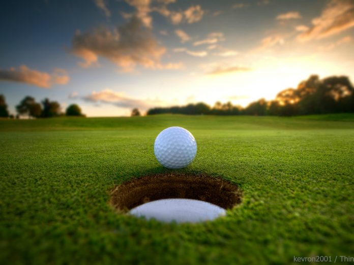golf ball rolling into hole with beautiful sunset in the background