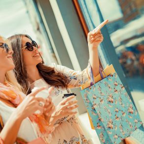 Happy woman with shopping bags pointing finger in the shop window.