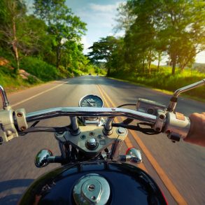 Driver riding motorcycle on an asphalt road through