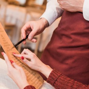 Cropped image of customer asking waiter about food in menu