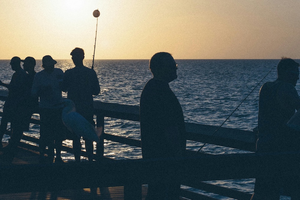 Fishing on a pier at sunset.