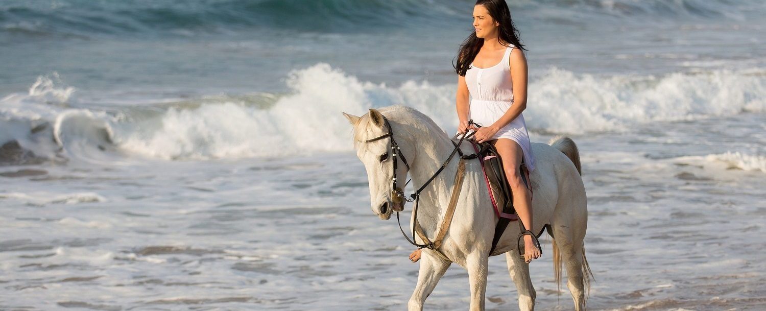 young lady riding horse on beach