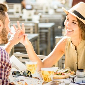 Couple in love having fun at beer bar on travel excursion - Young happy tourists enjoying happy moment at street food restaurant - Relationship concept with focus on girl face on warm bright filter