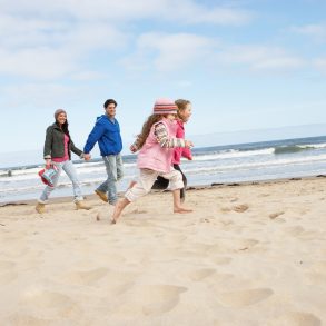 family running on beach in winter