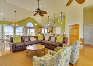 living room with green decor, rug, couches, kitchen