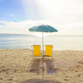 Two beach chairs on the sand.