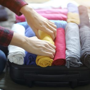 Woman hand pack clothes in suitcase bag on bed, prepare for new journey.