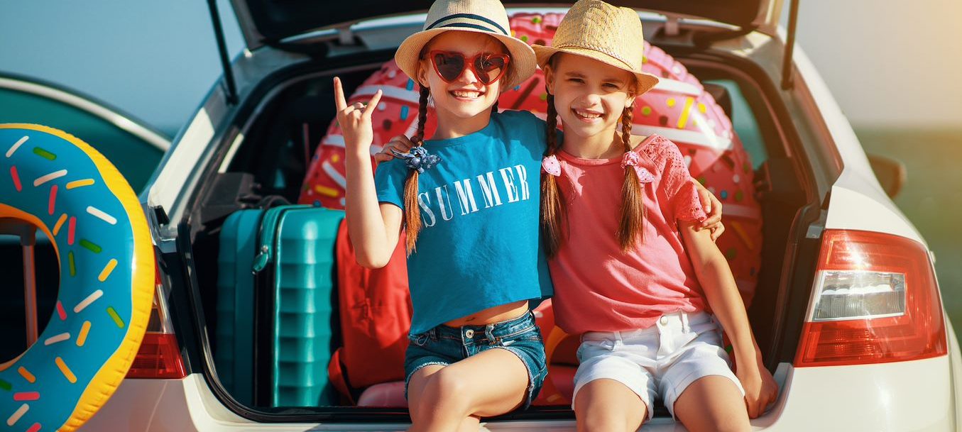 two kids smiling at the back of car, road trip, why obx is the perfect raleigh getaway