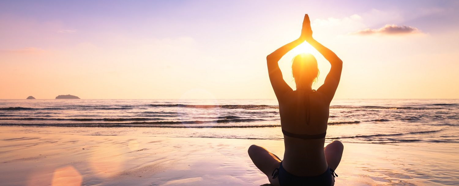 Woman enjoying beach yoga on OBX at sunset