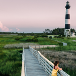 girl standing on boardwalk at bodie island lighthouse