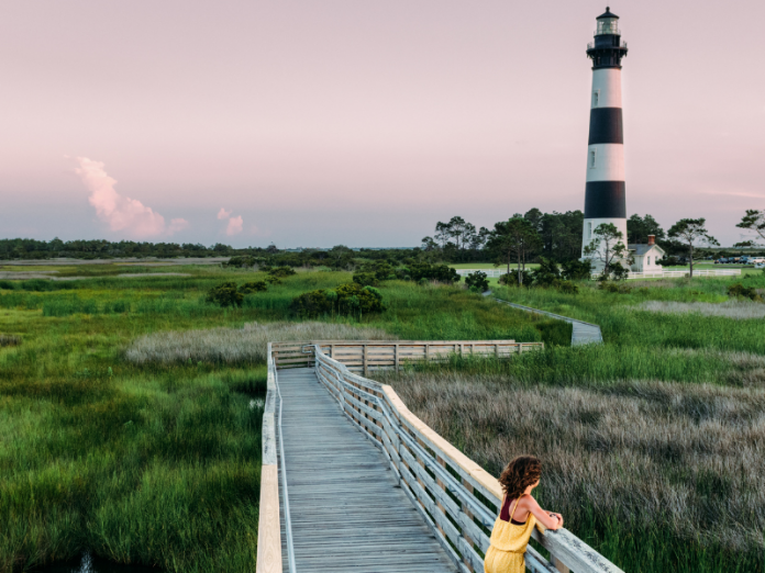 girl standing on boardwalk at bodie island lighthouse