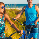 man and woman with bikes on beach path