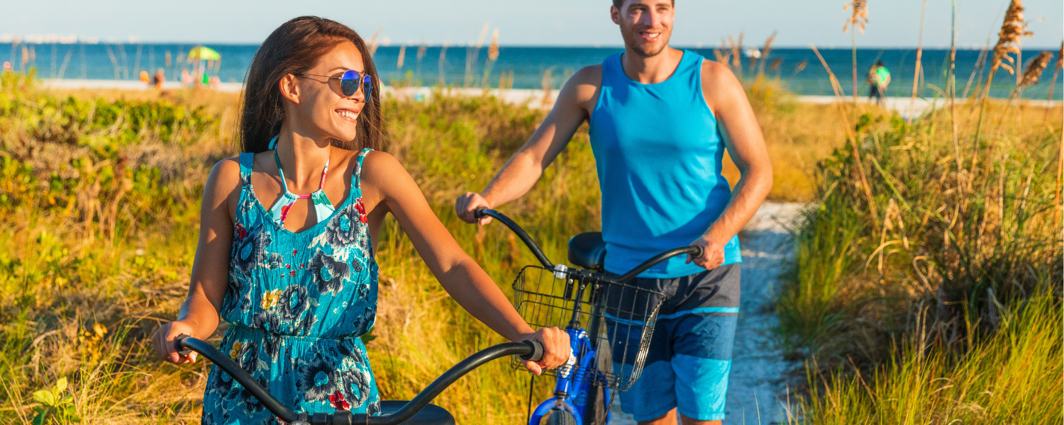 man and woman with bikes on beach path