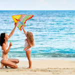 mother and daughter flying kite on beach