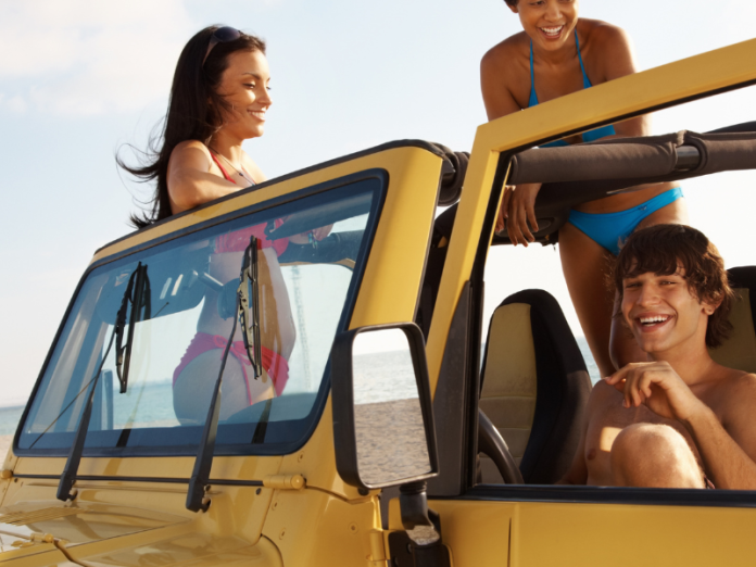 three people in jeep on beach