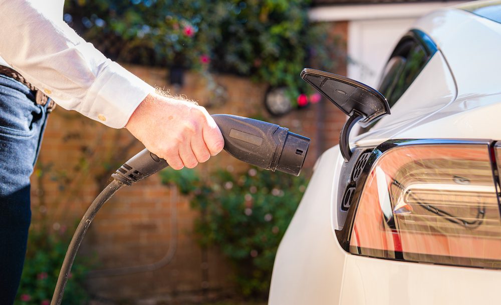 Man charging electric car at home