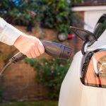 Man charging electric car at home