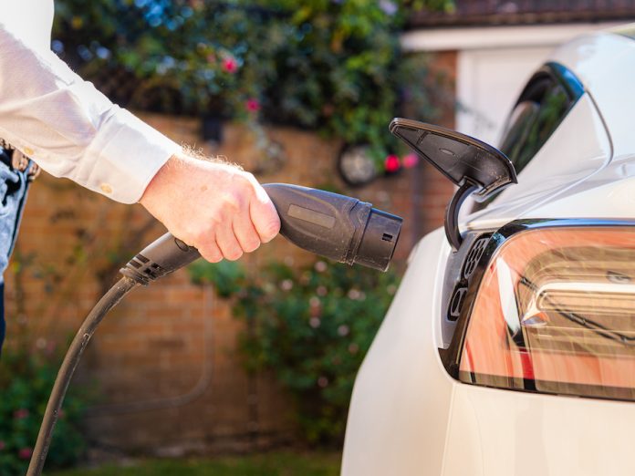 Man charging electric car at home