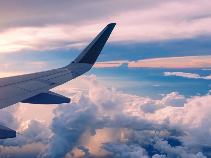 Close-up of airplane wing flying at sunrise