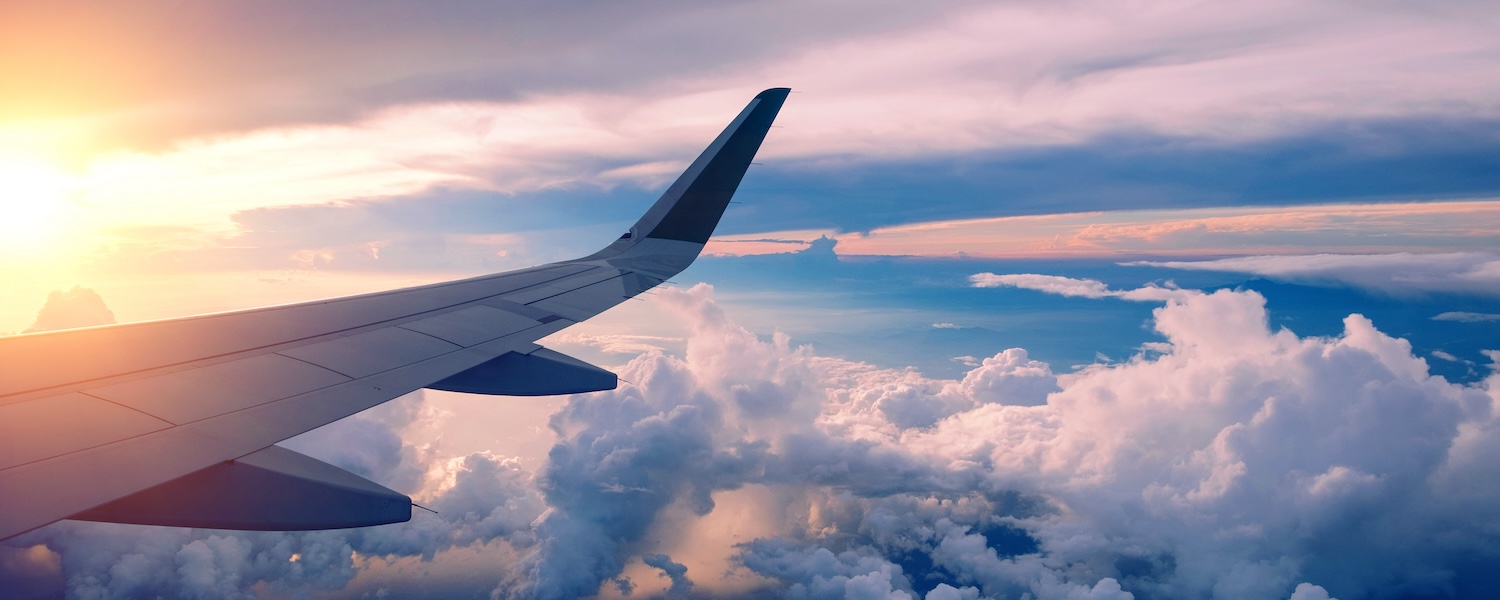 Close-up of airplane wing flying at sunrise