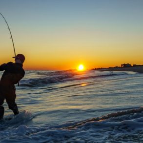Silhouette of a man surf fishing