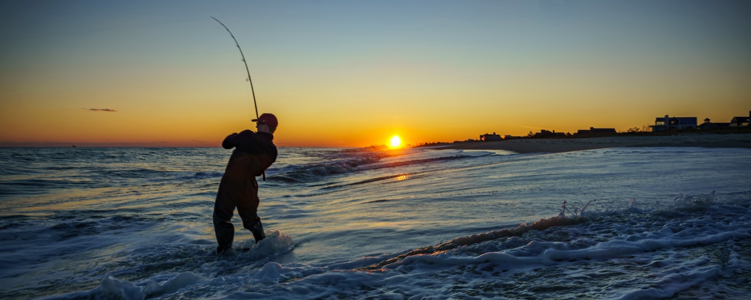 Silhouette of a man surf fishing