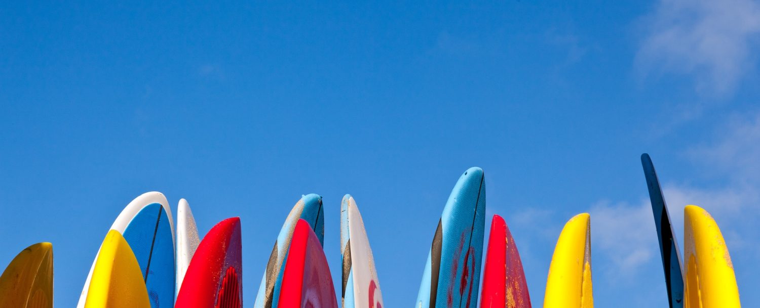 Outer Banks Beach equipment rentals surf boards in a stack against a blue sky