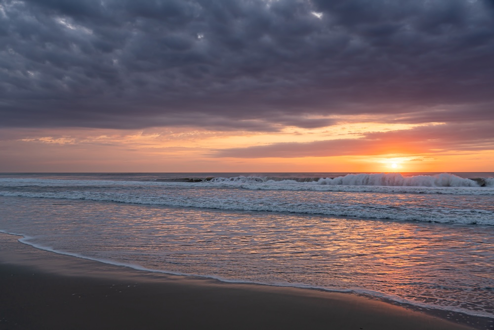 Dramatic sunrise over breaking waves on the beach in Corolla, North Carolina. 